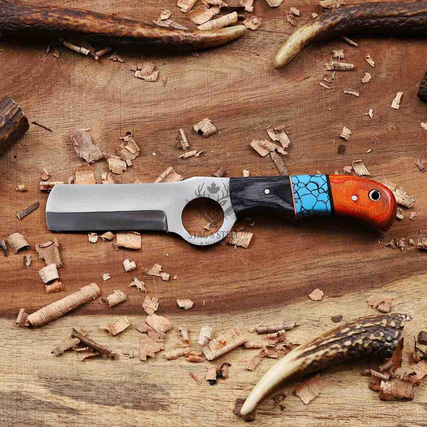 Decorative knife with a multicolored handle on a wooden surface with antlers and wood shavings.