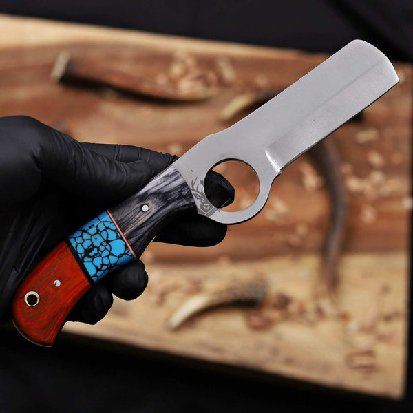 Hand holding a knife with a unique handle design on a wooden surface.