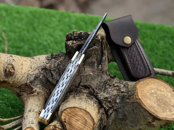 Folding knife with a leather sheath on a wooden surface