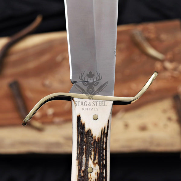 Brass S-guard and stag antler handle on a D2 bowie knife