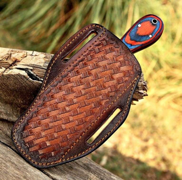 Brown leather sheath with a colorful bird head design on a wooden surface.