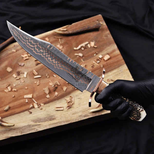 copper damascus bowie knife held in hand