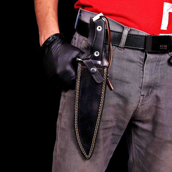 D2 steel bowie knife in black leather sheath with leather cord wore by maker vertical on his left side
