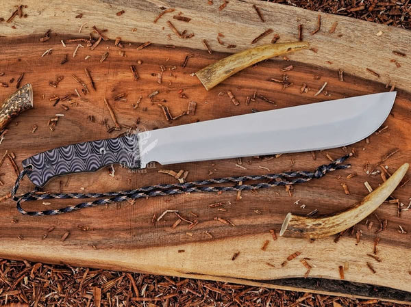 Full view of D2 machete knife with Grey Micarta handle, satin blade, and paracord on wood background