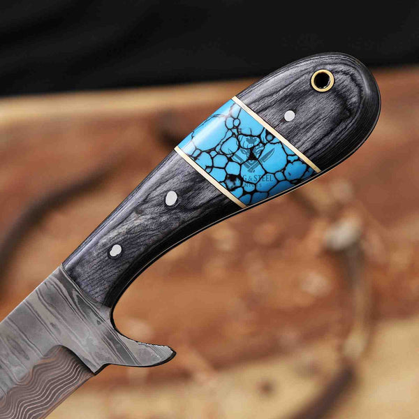 Knife with a decorative handle featuring blue and gold inlay on a blurred natural background