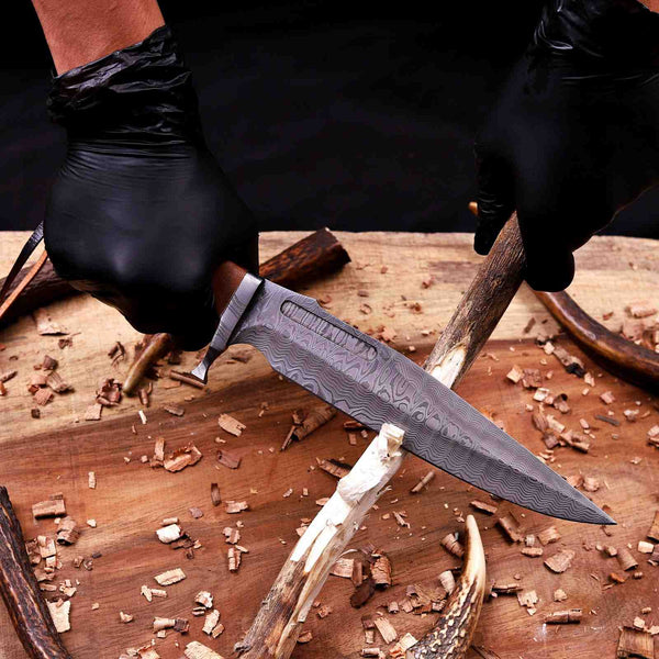 Forged VG10 Damascus bowie blade pattern shown over a cutting of firewood