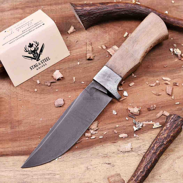 Handmade D2 fixed blade hunting knife on workbench with wood shavings