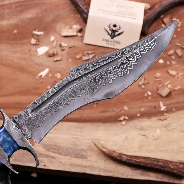 Gloved hand holding handmade Damascus finger guard bowie knife over wooden board