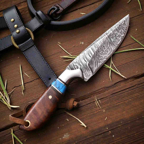 Custom fixed blade Damascus knife with a polished wood handle, turquoise accent, and patterned steel blade displayed beside a leather sheath.