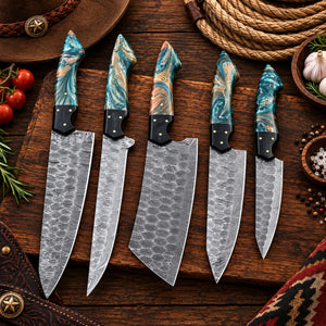Damascus kitchen knife set laid out on rustic wood with tomatoes and garlic