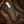 Cowboy knife with white crackle-pattern handle in an ornate leather sheath on a rustic wooden Western background