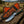 Decorative knife with floral patterns in a leather sheath on a wooden surface, with a blurred natural background.