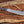 Damascus machete with layered G10 handle and paracord lanyard on rustic wood