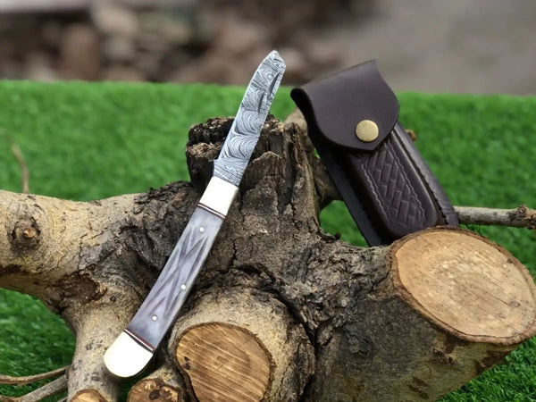 Knife with a decorative blade and leather sheath on a wooden log