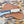 A fixed-blade knife with a textured silver blade and cream handle, resting on a brown leather sheath over a leopard-print surface.