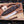 Fixed-blade steel knife with a brown wood handle and embossed dark brown leather sheath, displayed on a wooden board with stag antlers