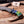 A custom San Mai Damascus steel Bowie knife with a vibrant blue, green, and yellow marbled handle, displayed on a rustic wooden board with wood shavings and antler props. A brand card for 'Stag Steel Knives' is visible in the background.