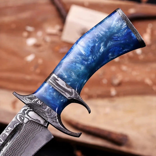 Close-up of blue marbled resin handle and Damascus spacer on finger guard bowie knife