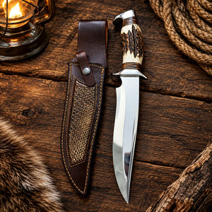 Handmade stag handle Bowie knife with D2 clip point blade beside a tooled leather sheath