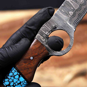 Hand holding a knife with a wooden handle and Damascus steel blade against a blurred background