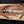 Copper Damascus Bowie knife laying horizontally on wooden surface 