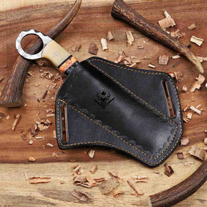 Black leather case with a hunting knife on a wooden surface with wood shavings.
