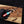 Hand holding a knife with a wooden handle and metal blade, branded 'Stag & Steel', on a wooden surface.