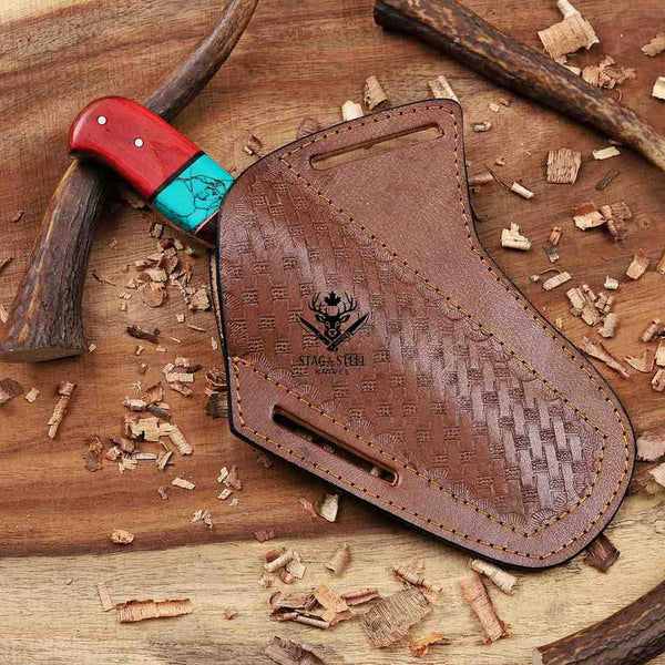Brown leather sheath with red and turquoise handle on a wooden background