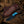 Knife with blue handle and brown leather sheath on wooden surface with cowboy hat and rope.