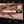 D2 Arkansas toothpick bowie knife with black G10 handle beside its leather sheath