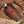 Brown leather case with embossed pattern on a wooden surface with wood shavings