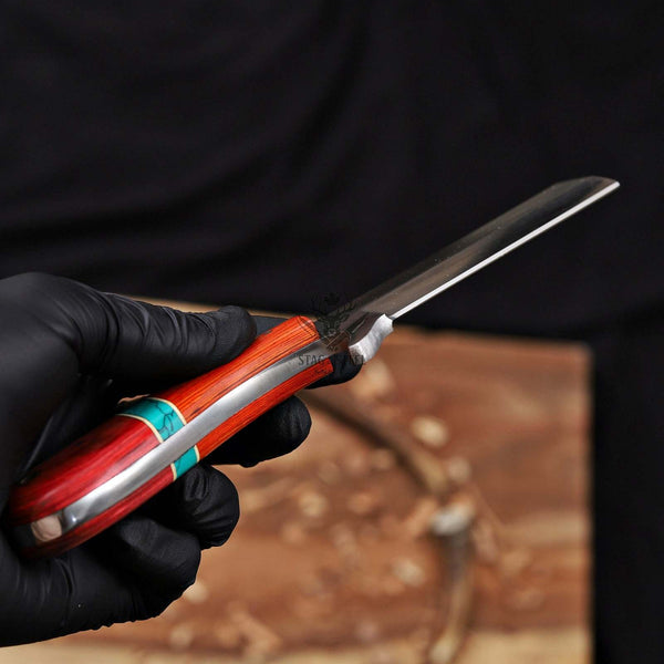 Hand holding a knife with a red handle against a blurred background