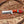 Wooden-handled knife with red and blue accents on a wooden surface with wood shavings.