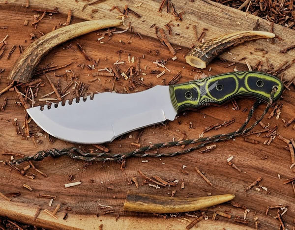 D2 steel tracker knife with Micarta handle, blade tip pointing left, notched spine, and paracord on wood background