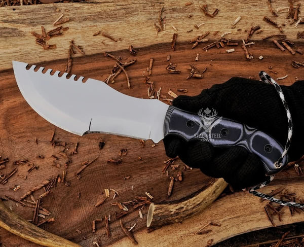 D2 tracker knife with black Micarta handle shown in hand for grip, blade shape, and size reference