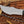 Close-up of mirror polished D2 tracker knife blade with notched spine, sharp edge, and black Micarta handle detail