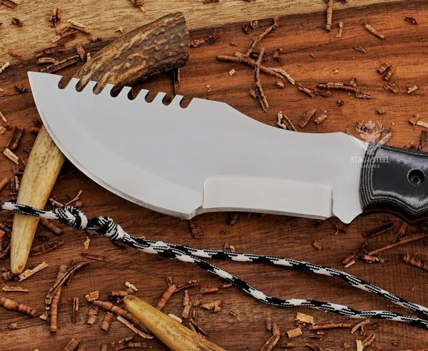 Close-up of mirror polished D2 tracker knife blade with notched spine, sharp edge, and black Micarta handle detail