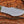 Close-up of mirror polished D2 tracker knife blade with notched spine, sharp edge, and paracord on wood background