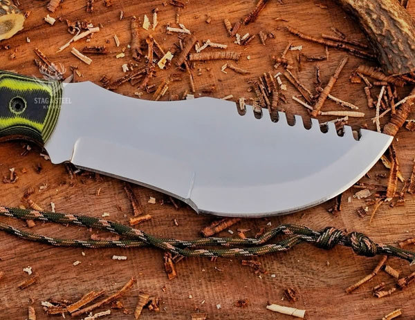 Close-up of mirror polished D2 tracker knife blade with notched spine, sharp edge, and paracord on wood background