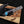Hand holding a Damascus steel knife with a blue inlay on a wooden surface.