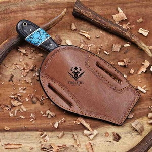Brown leather knife sheath with 'Stag & Steel Knives' logo on a wooden background with wood shavings.