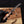 Hand holding a folding knife with wooden handle and metal blade on a wooden surface.