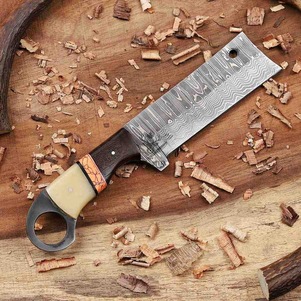 Decorative knife with a patterned blade on a wooden surface with wood shavings.