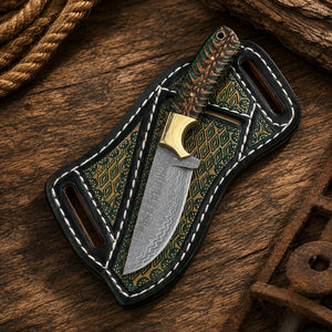 Damascus cowboy knife with green pine cone handle beside a black tooled crossdraw sheath