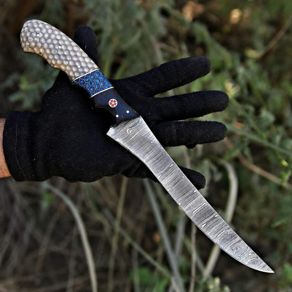 Hand holding fillet knife with a decorative handle against a natural background