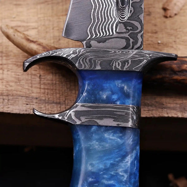 Macro of forged Damascus finger double guard and blue resin handle on bowie knife