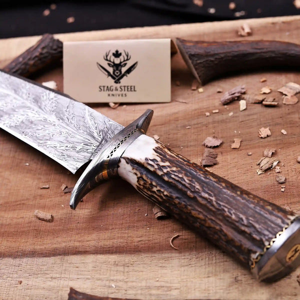 Feather Damascus blade meeting fire pattern guard and antler grip close-up
