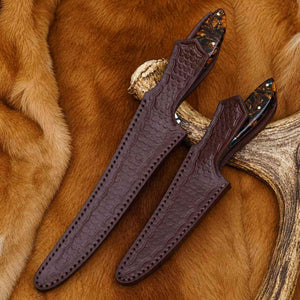 Two brown leather knife sheaths on a deer antler against a fur background
