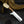 A fixed-blade knife with a polished silver blade, a dark brown wooden handle, and a natural beige horn or bone pommel, displayed diagonally on a dark textured surface with a horn prop in the background.