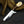 A fixed-blade knife with a polished steel blade and a dual-tone handle made of dark brown wood and cream-colored horn, resting on a dark textured surface with a dried animal horn prop.